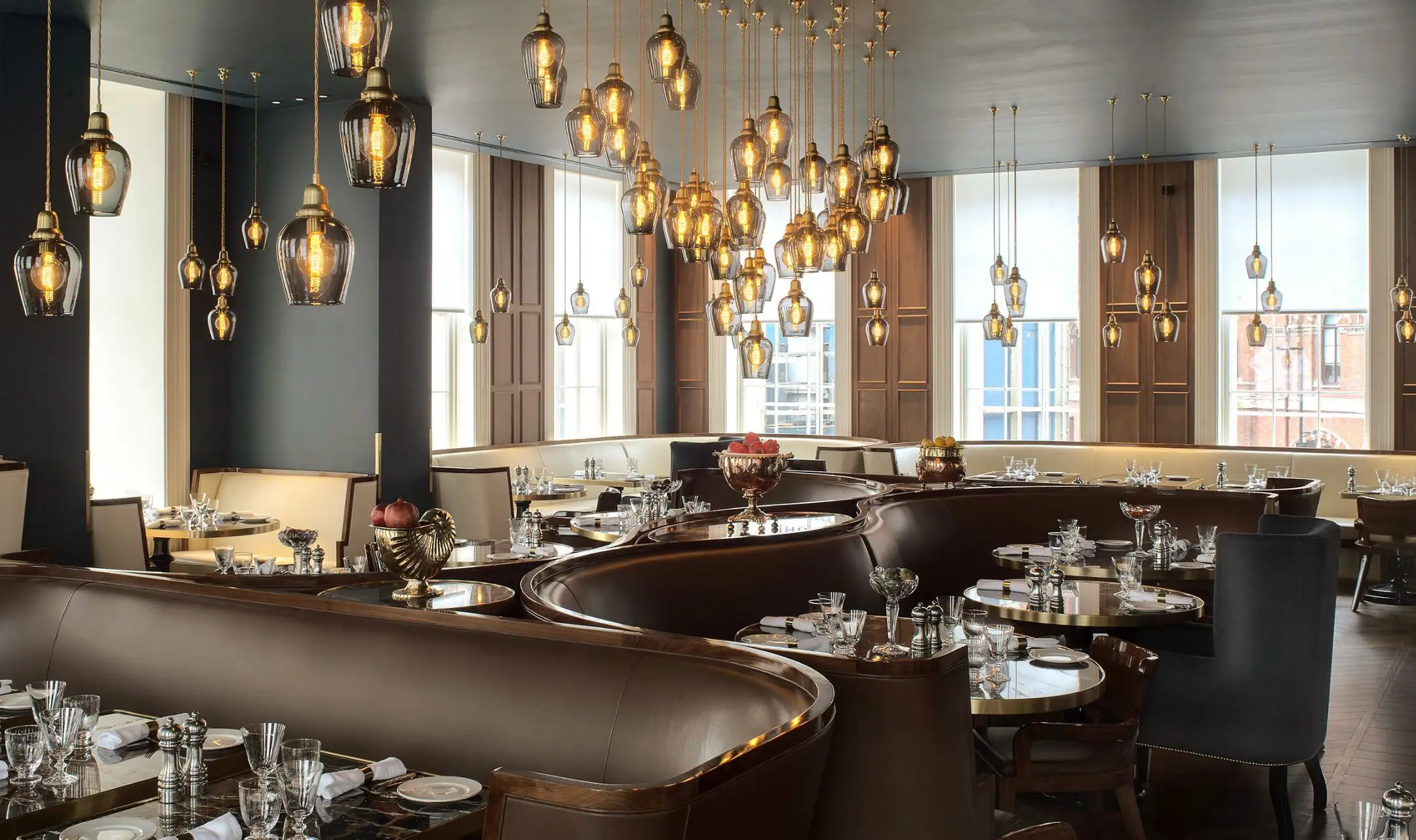 Un ristorante arredato dalla divisione contract: divanetti curvi in pelle, legno scuro e lampade di vetro sospese